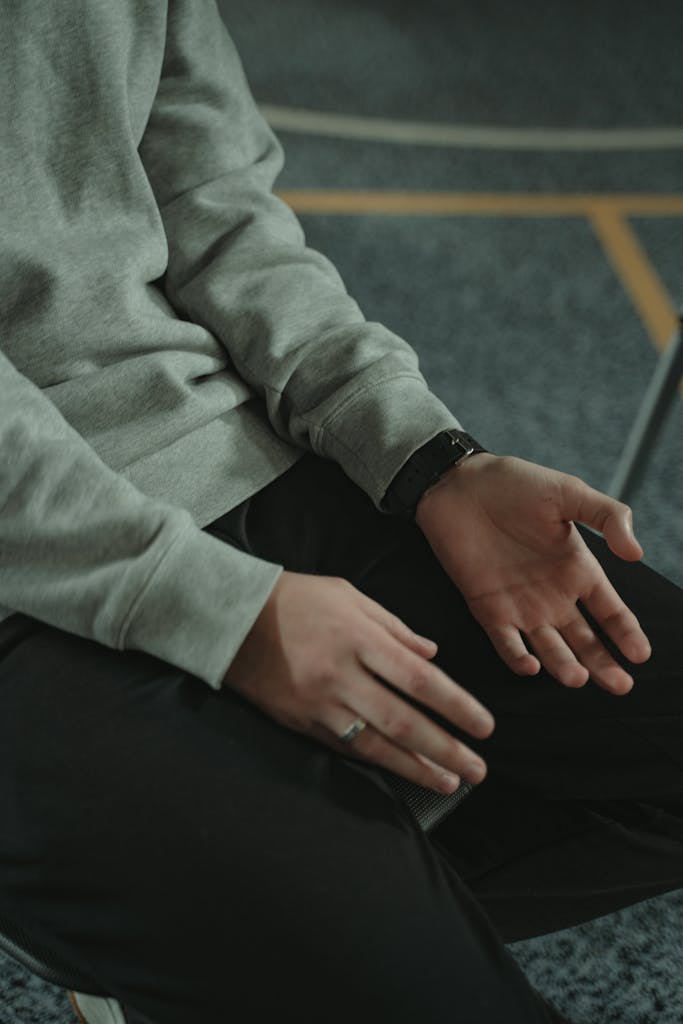 Person's hands resting thoughtfully on lap, expressing contemplation.